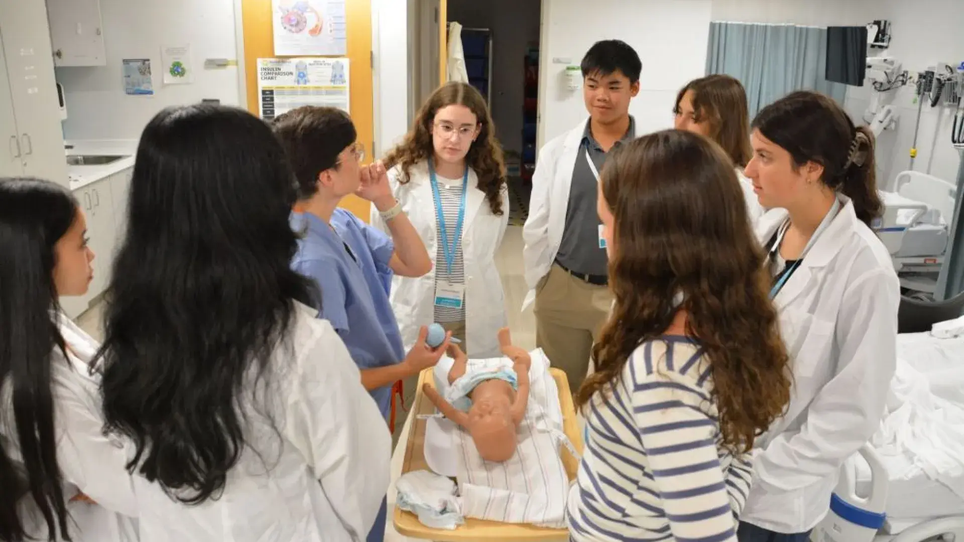 People in a medical setting look at an infant 