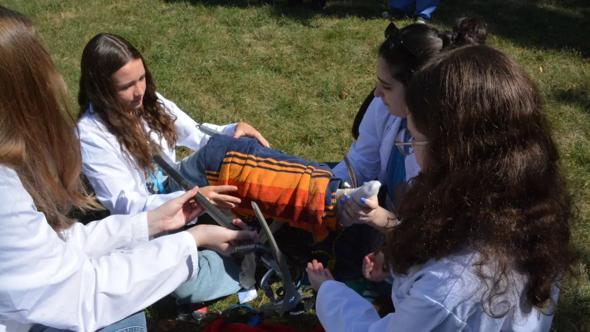Four people wearing lab coats wrap a towel around the leg of one of the people