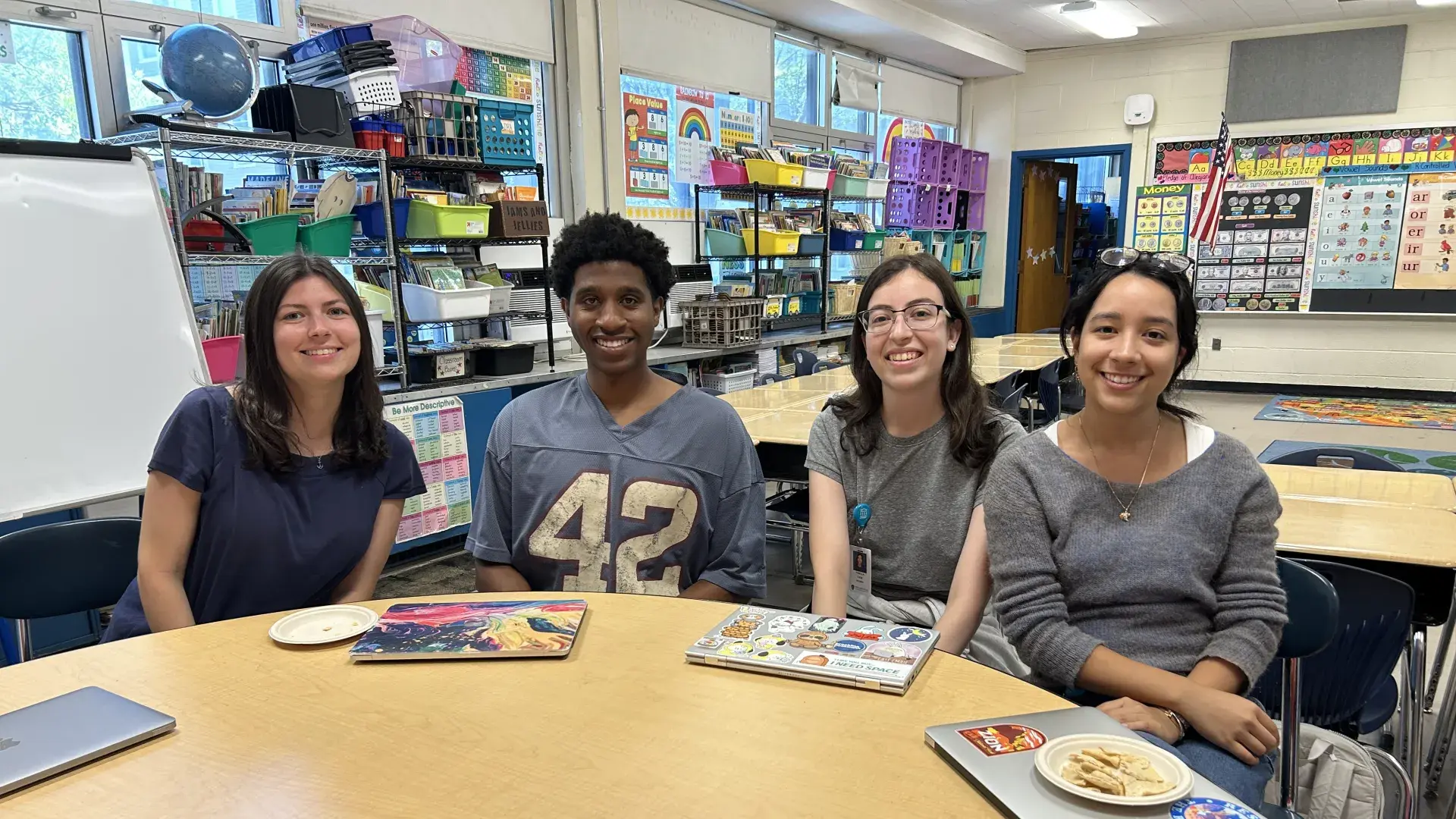 Four people sit at a classroom table