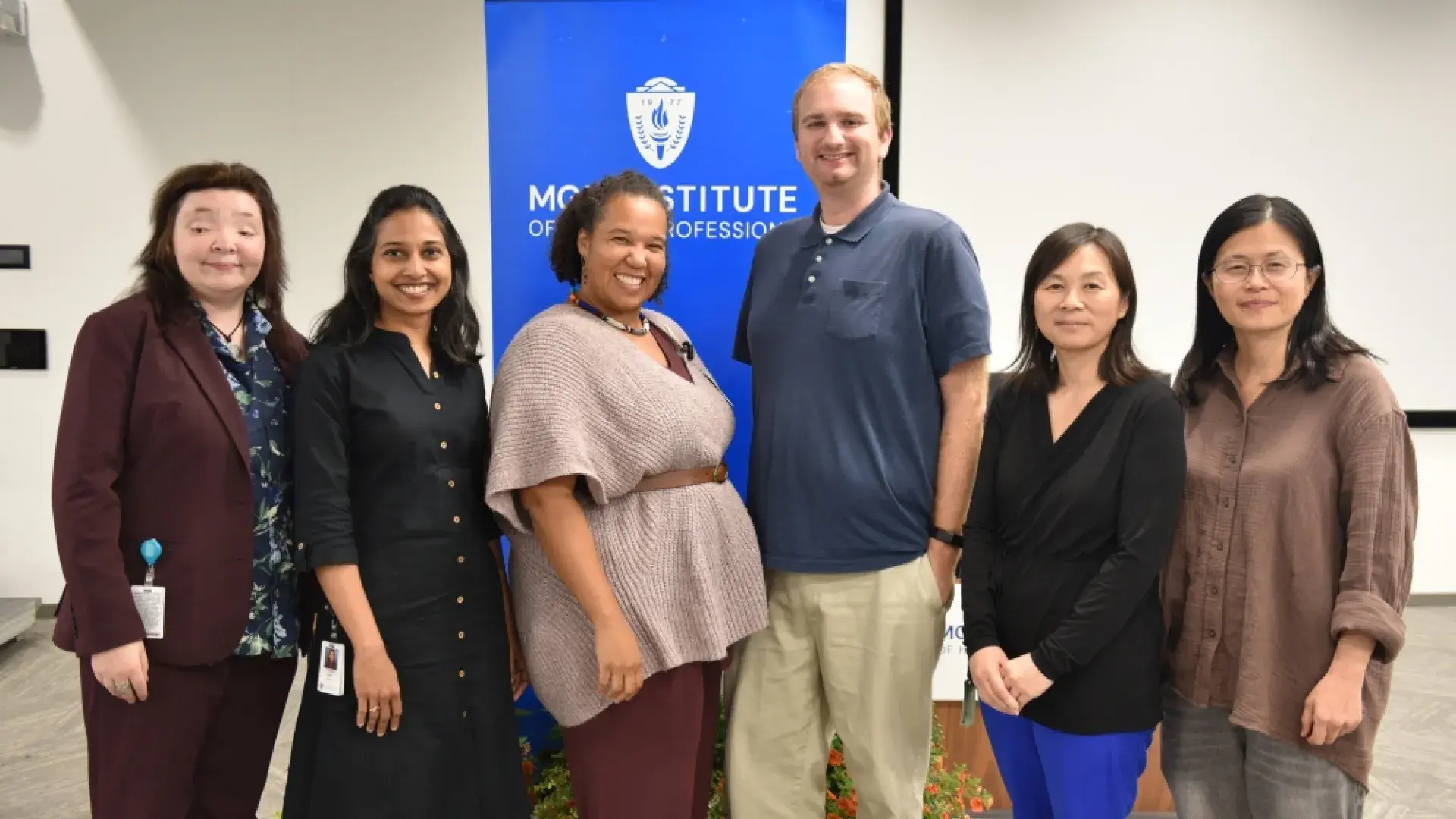 Six people stand in front of a banner that says MGH Institute