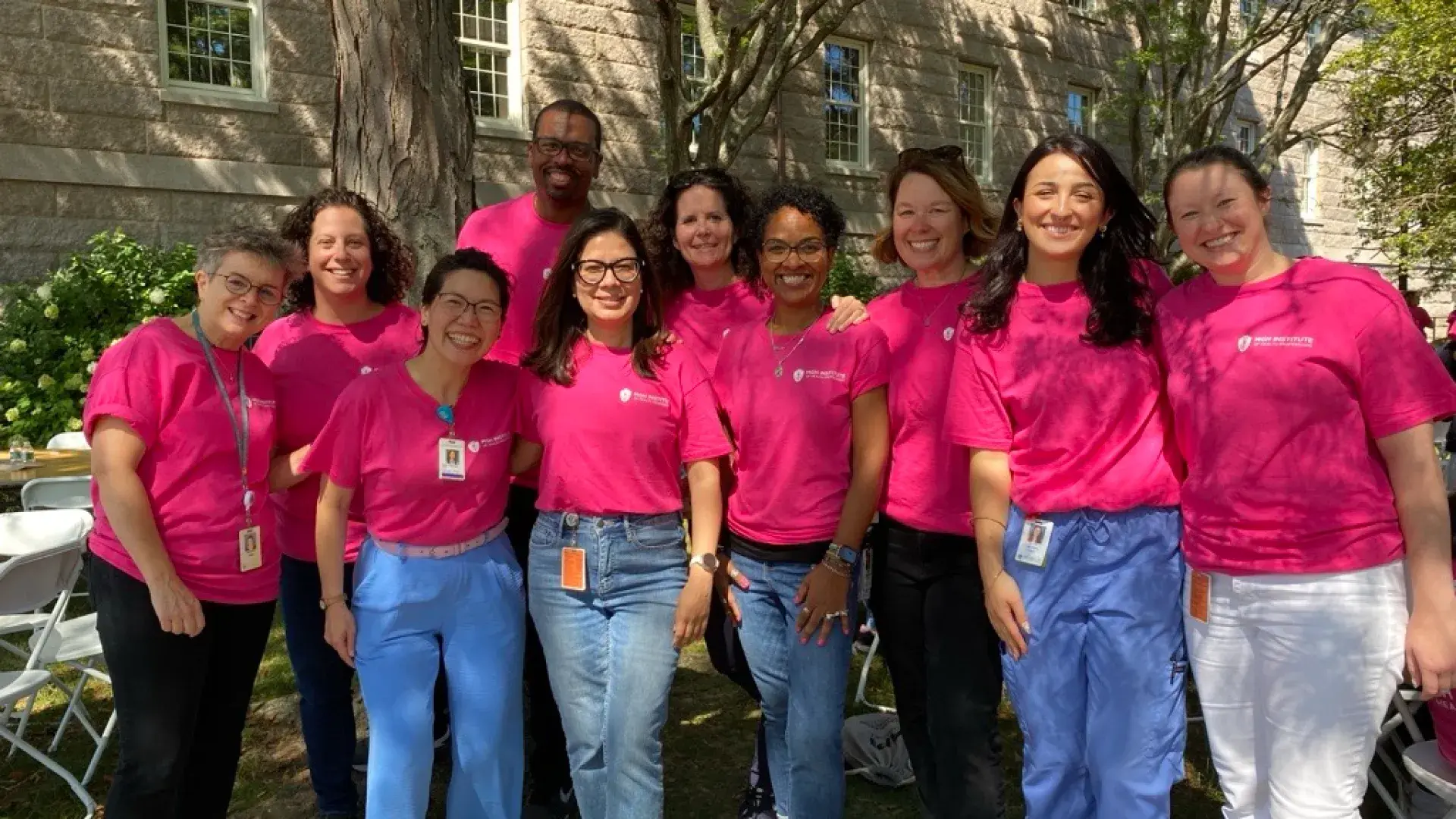Ten people in pink shirts post for the camera