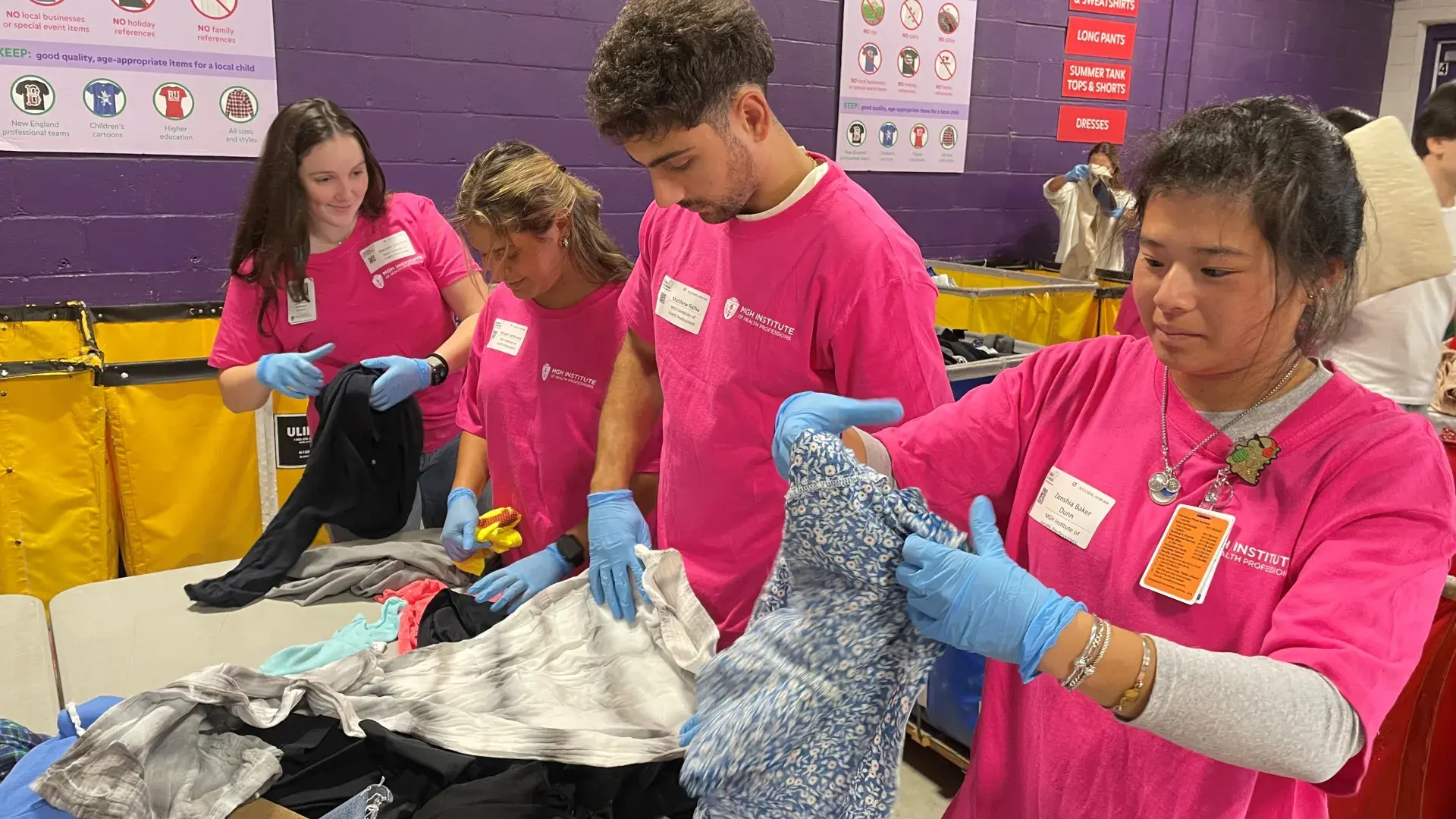 Four people handle clothes on a table
