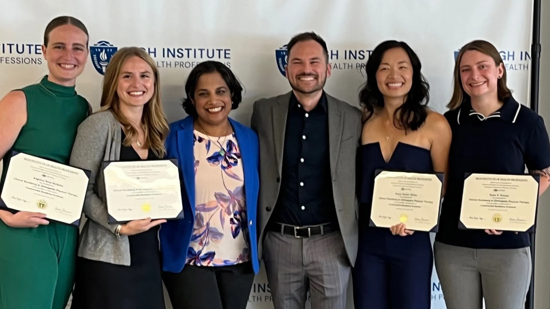 Six people stand together with four of them holding certificates