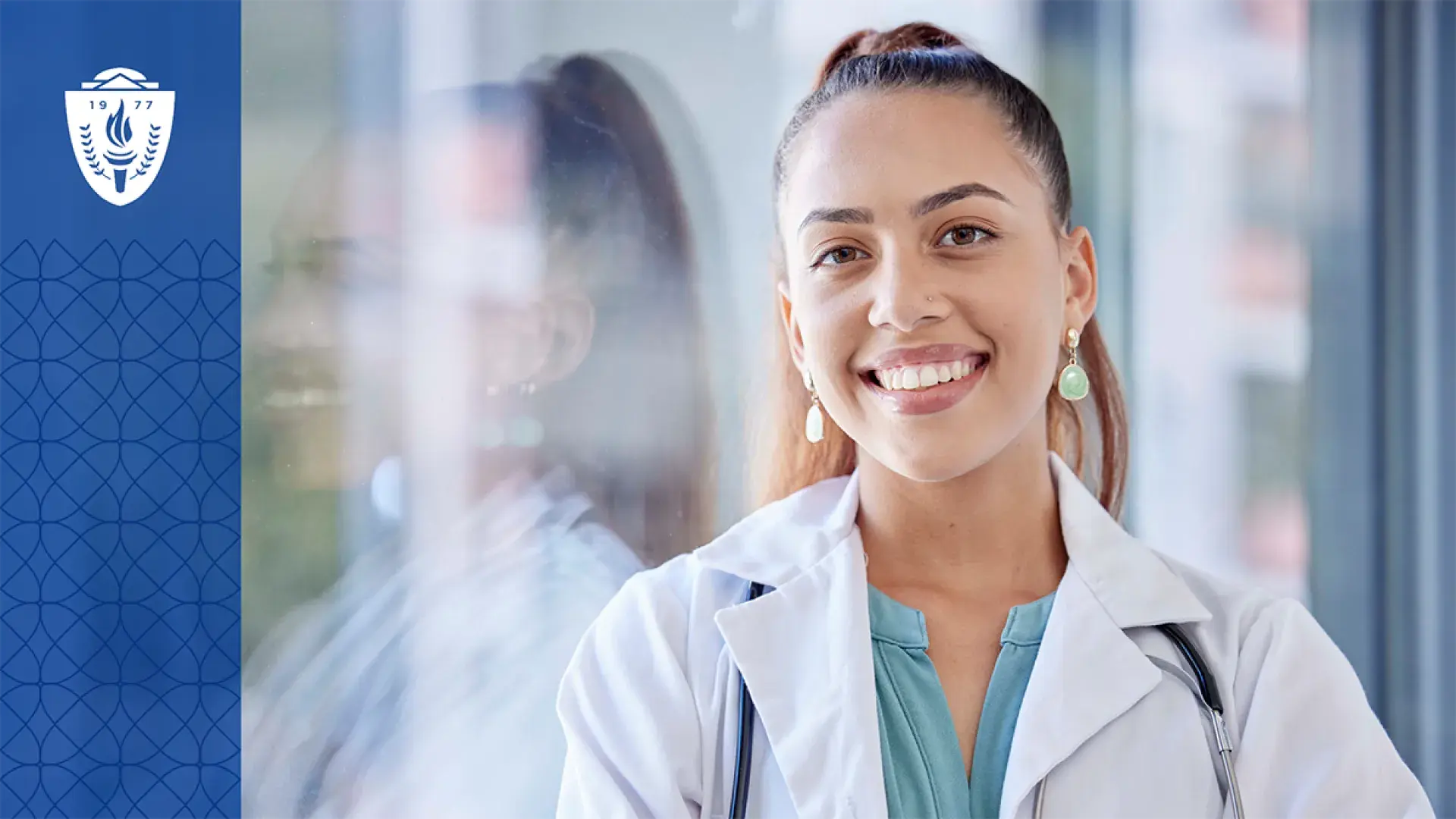 Headshot of woman wearing white lab coat and stethoscope smiling and looking at the camera