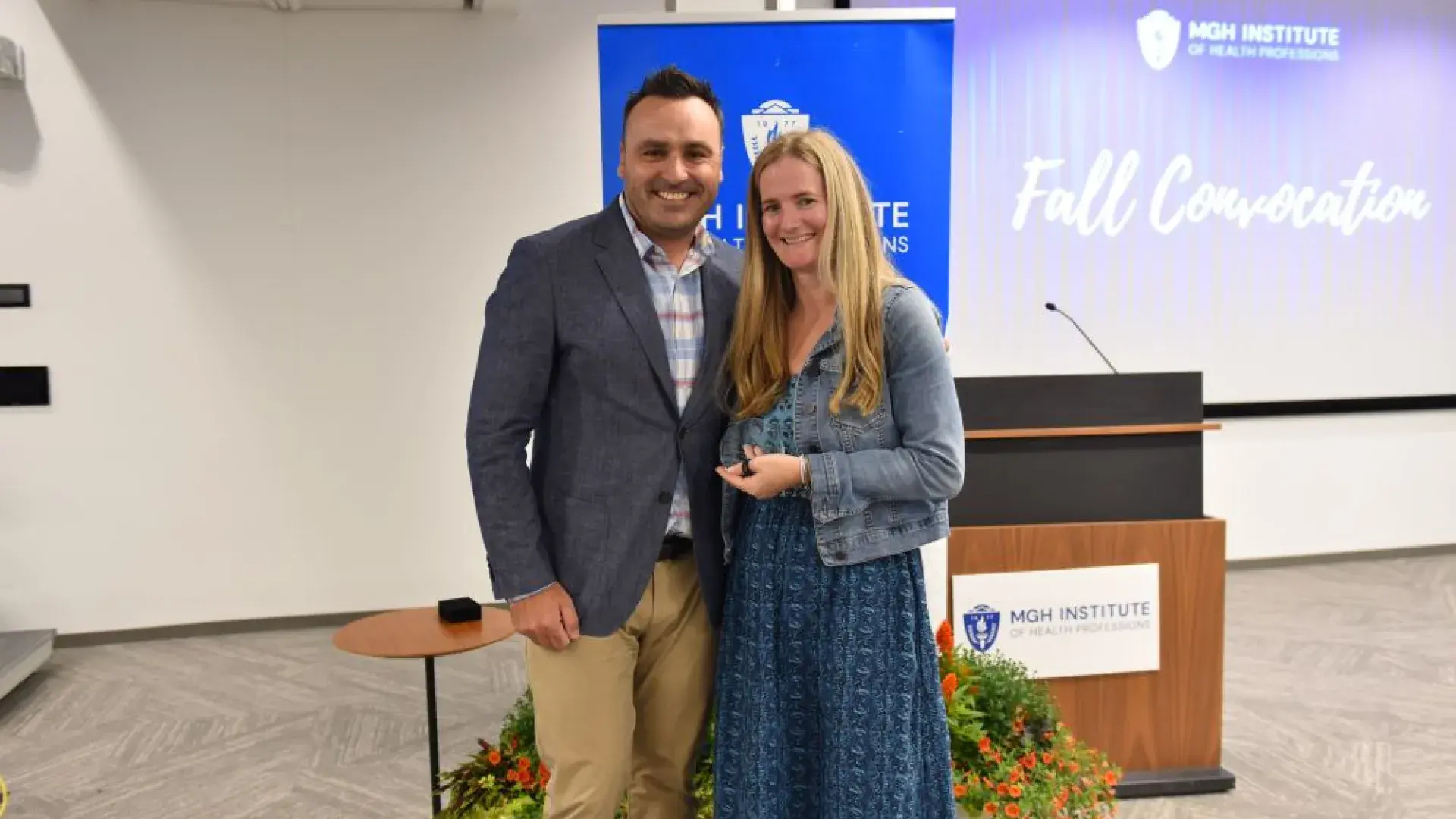 Man standing with woman in from of MGH Institute backdrop 