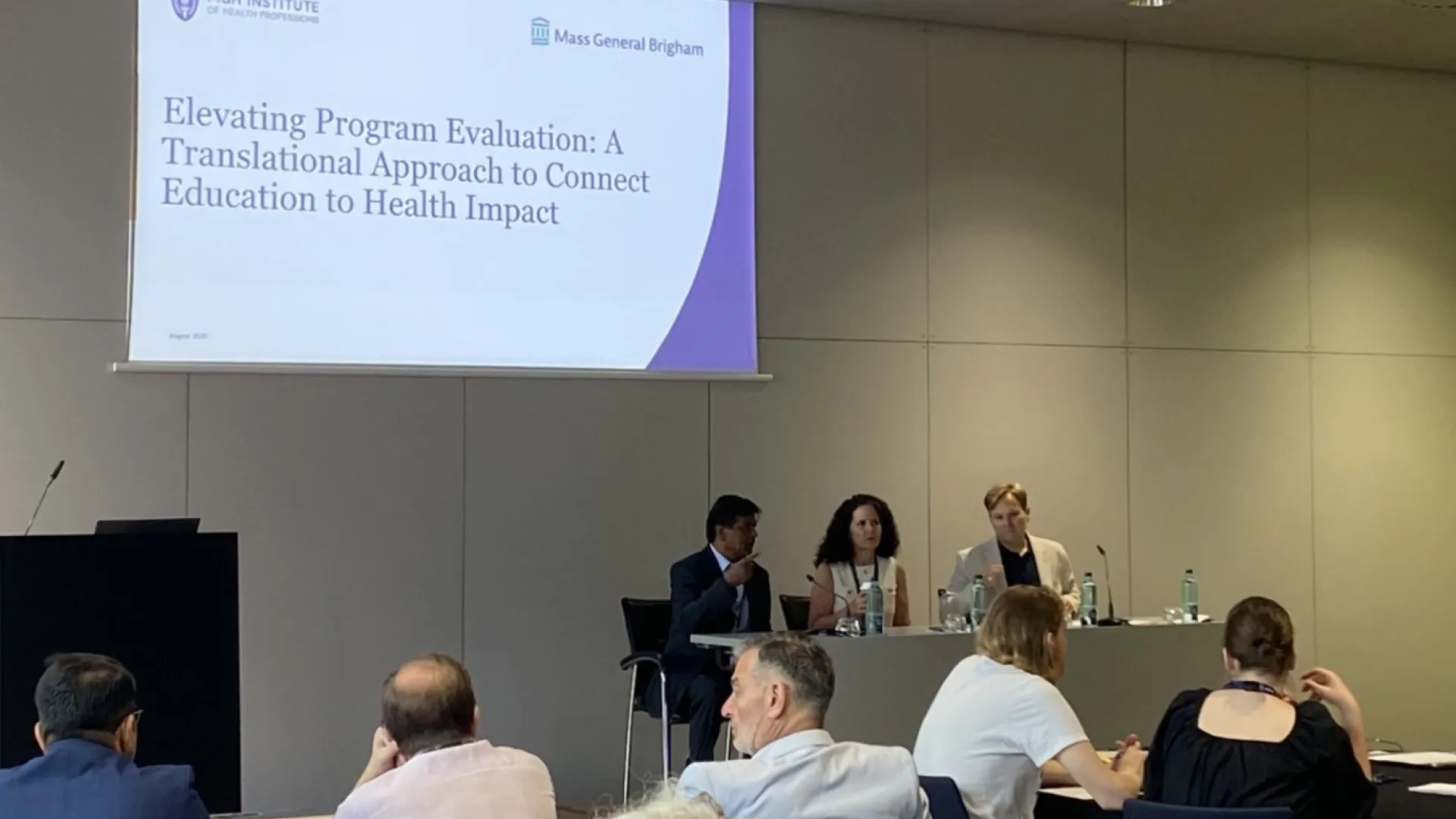 3 people at a table in front of a screen