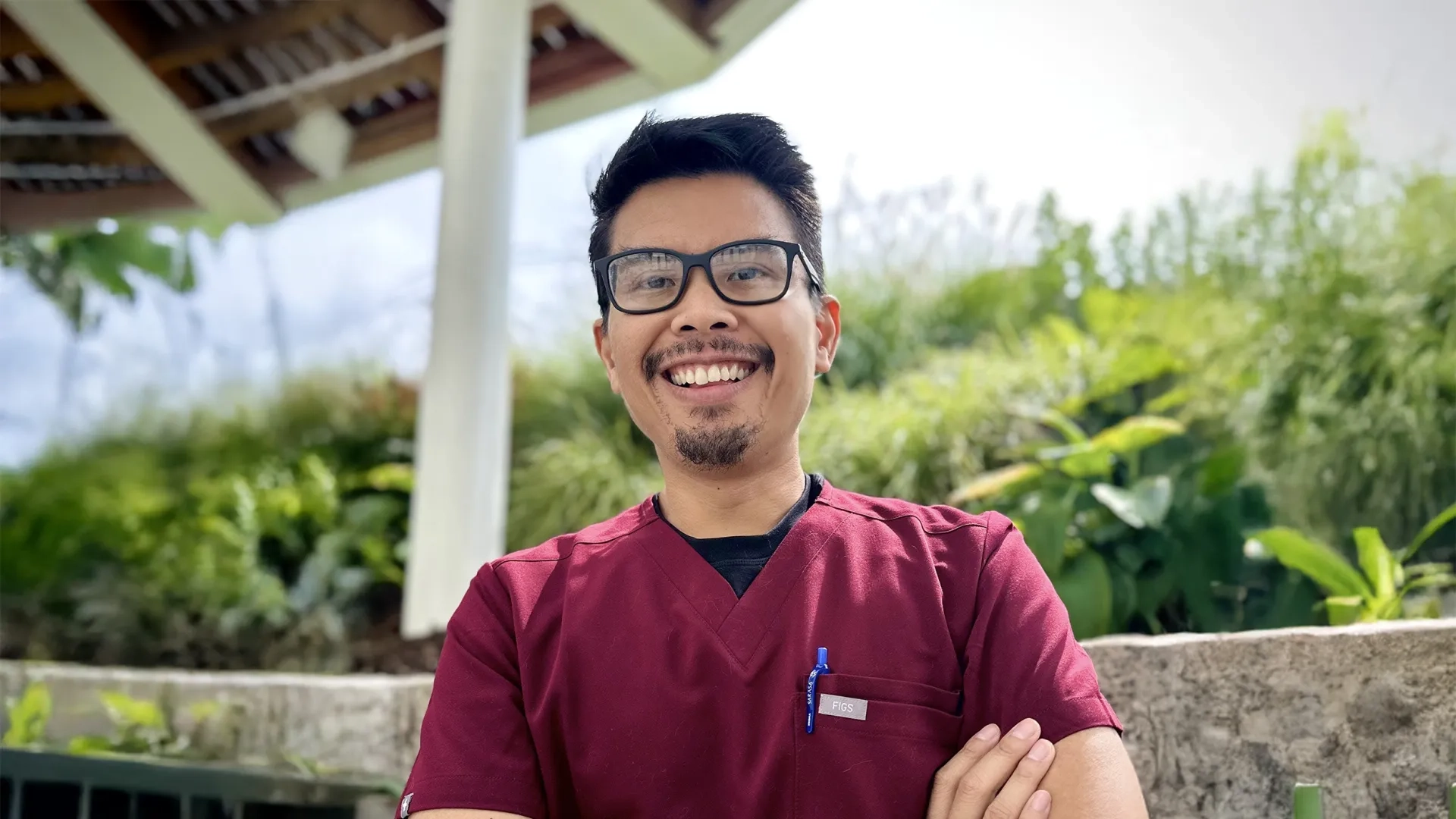 Man standing with big grin in a tropical location with arms folded