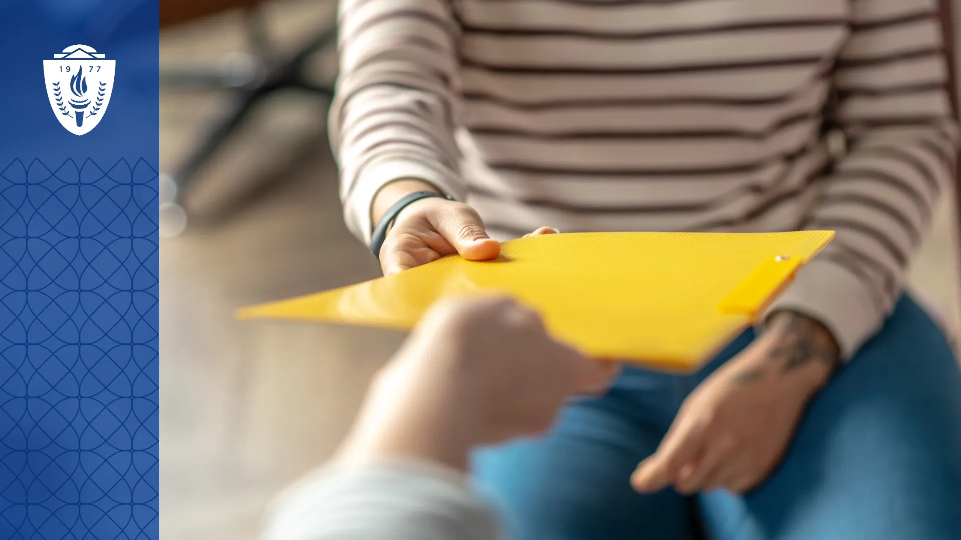 Close up of a person handing a yellow folder to another person.