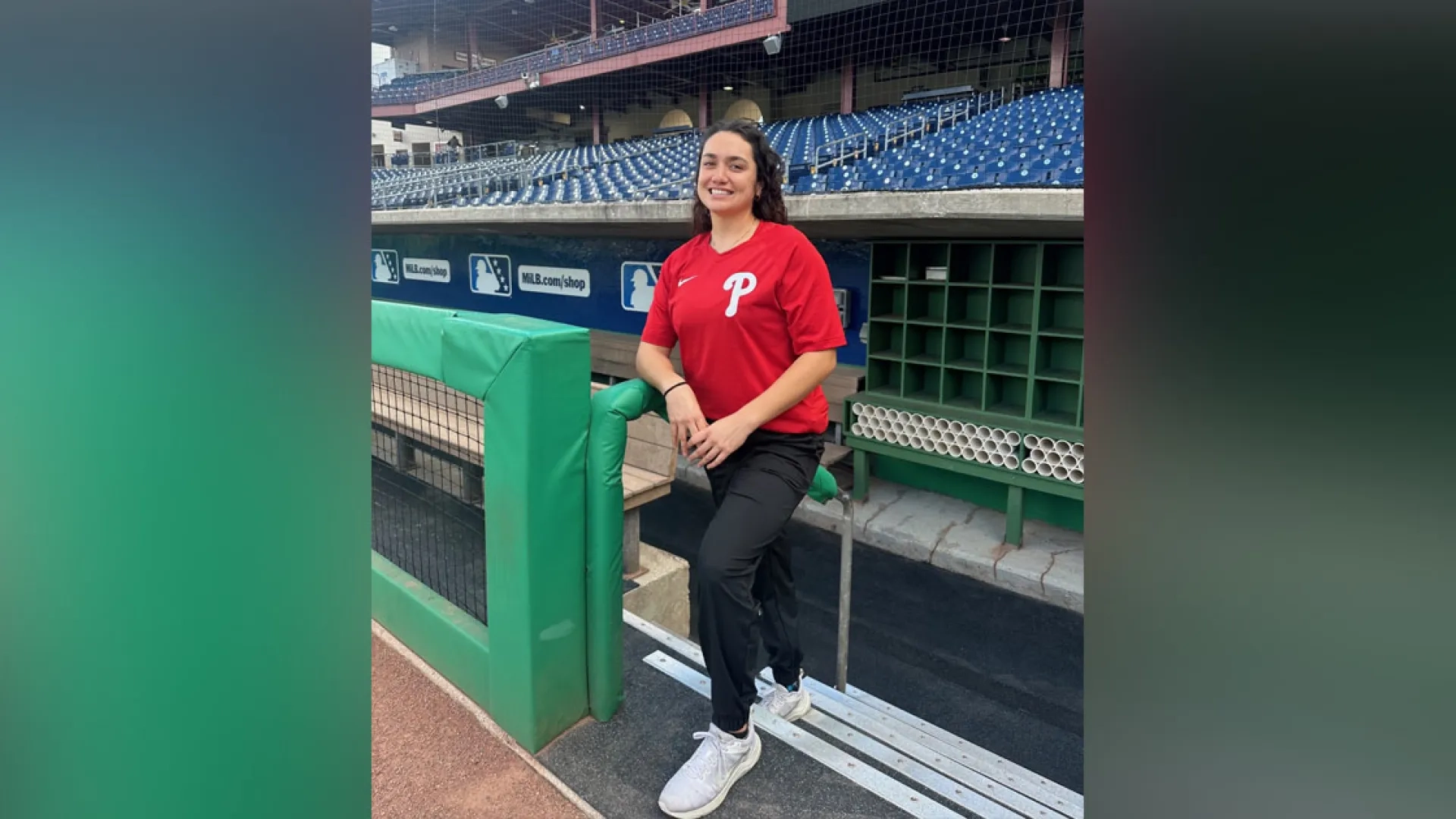 A woman stands on the stairs of a baseball field dugout