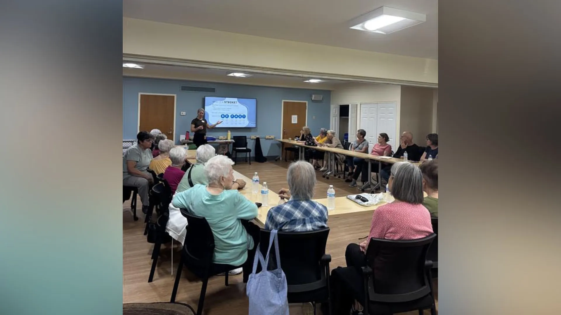 woman in front of smart board in room full of people