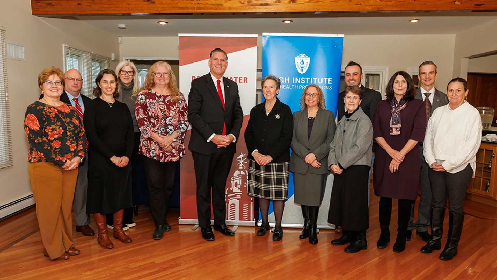 A group of people stand in front of banners in two rows