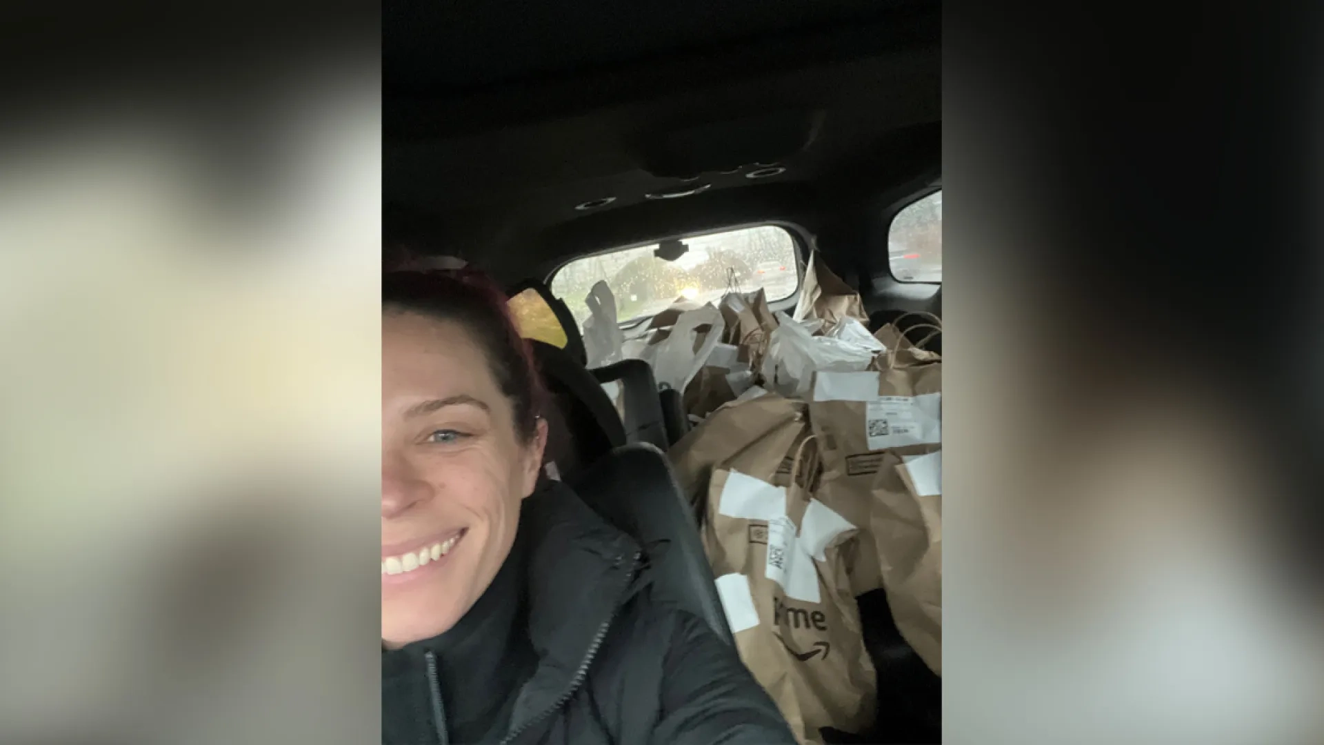 A woman in a car with a backseat full of paper bags