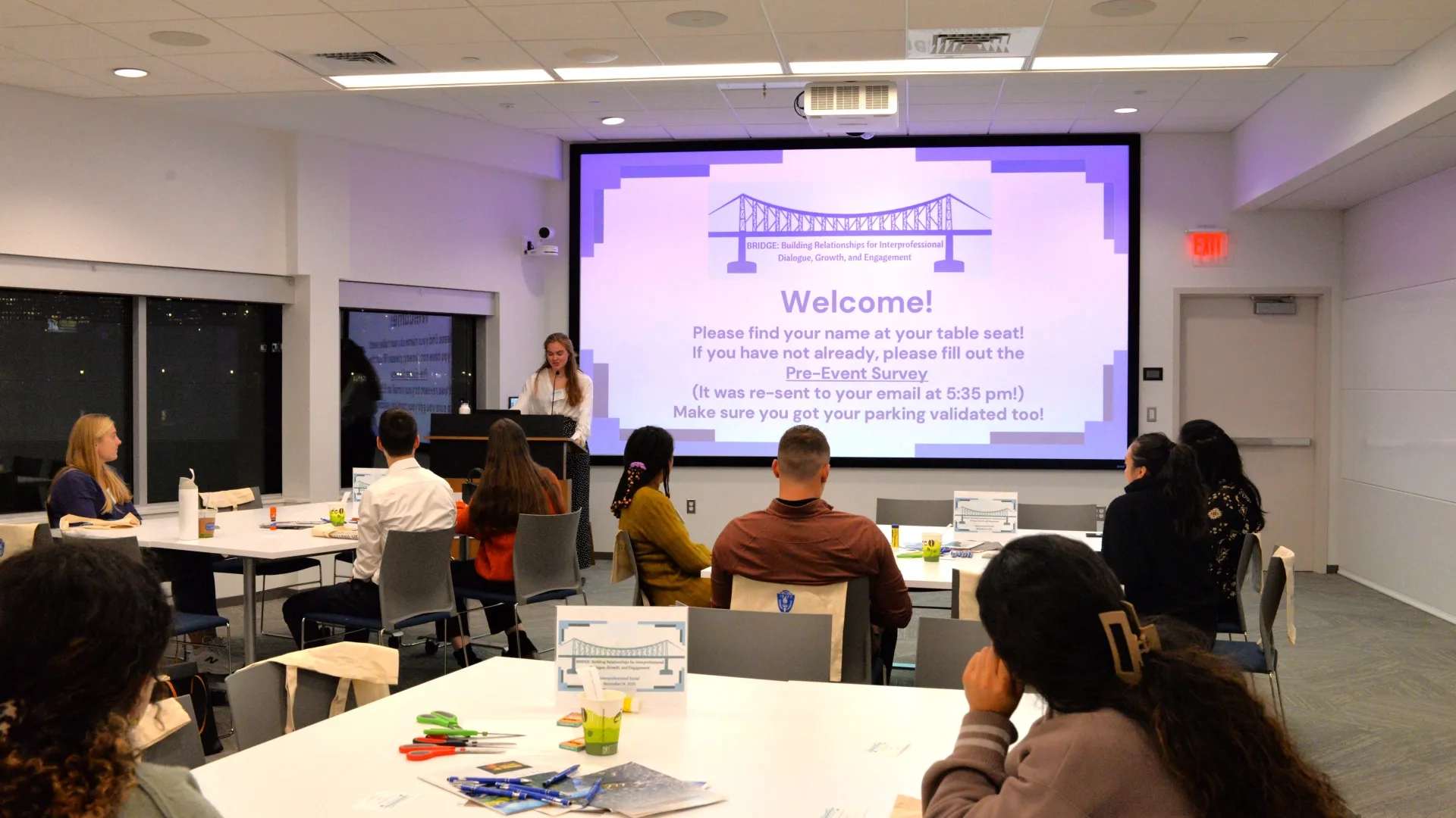 Wide shot of people sitting at tables in large room 