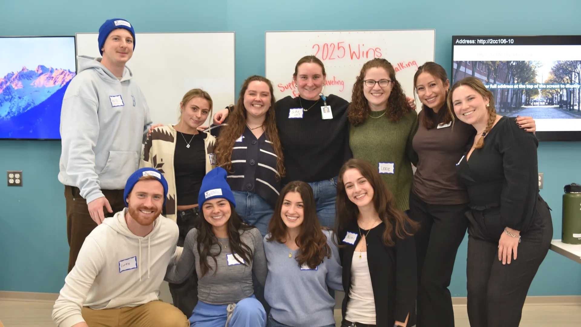 Eleven people pose in front of a board that says 2025 wins