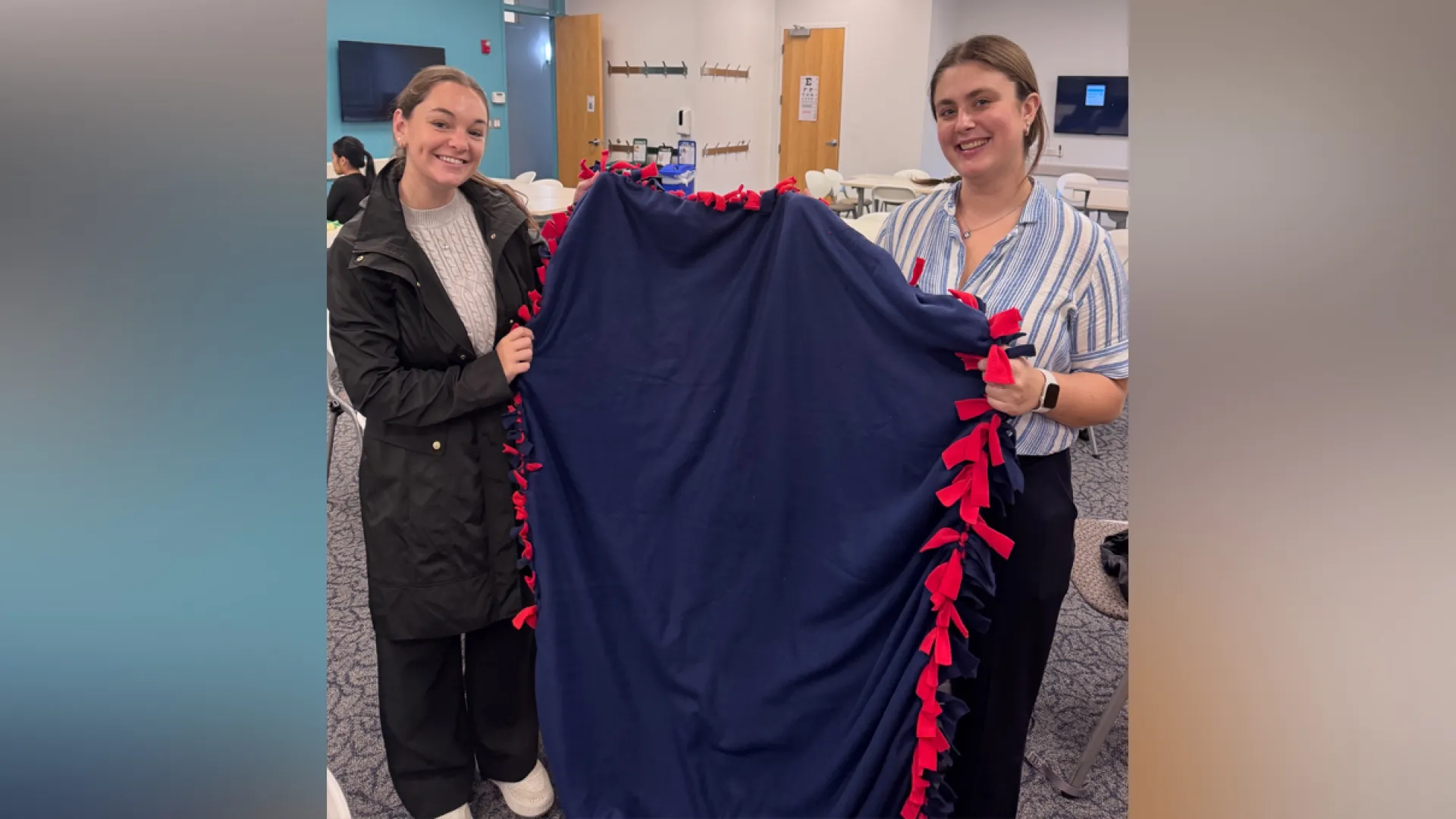 Two women hold a blanket between them