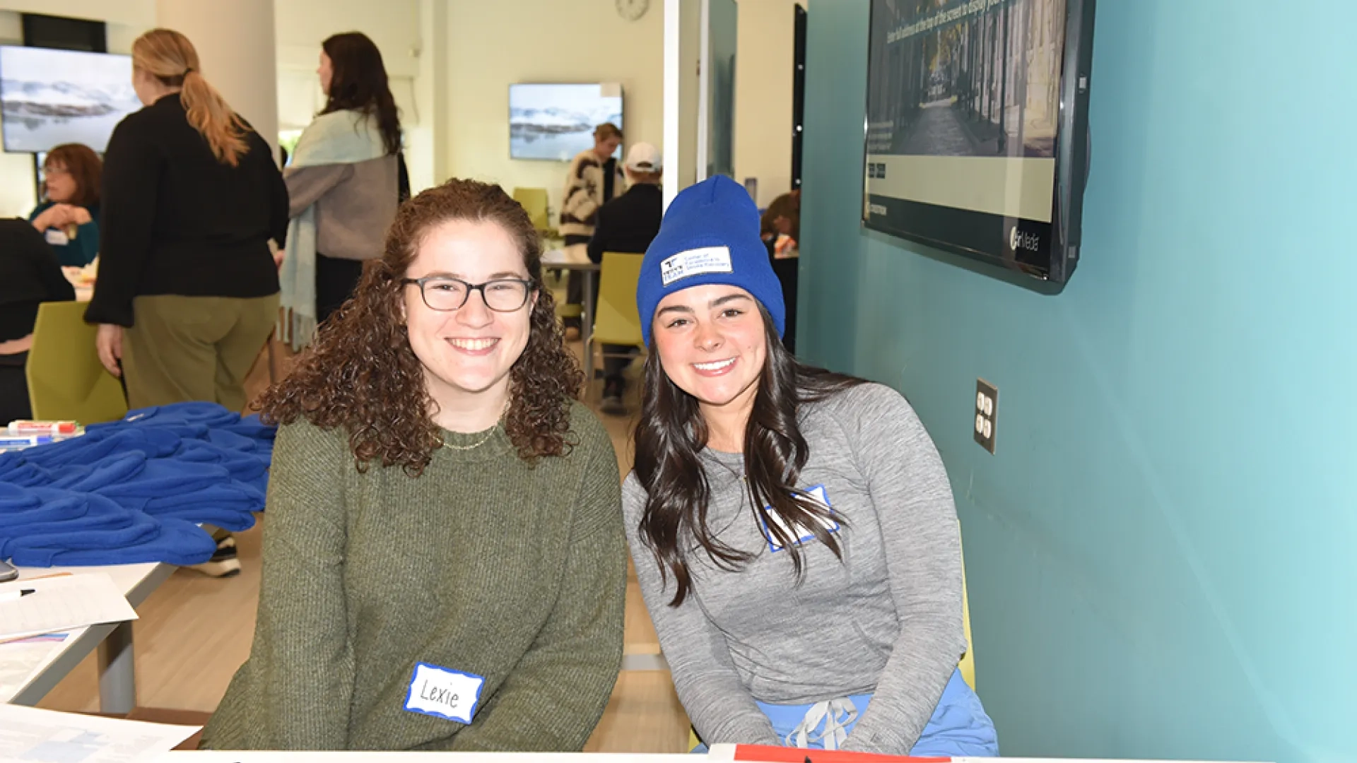 Two women sit behind a table
