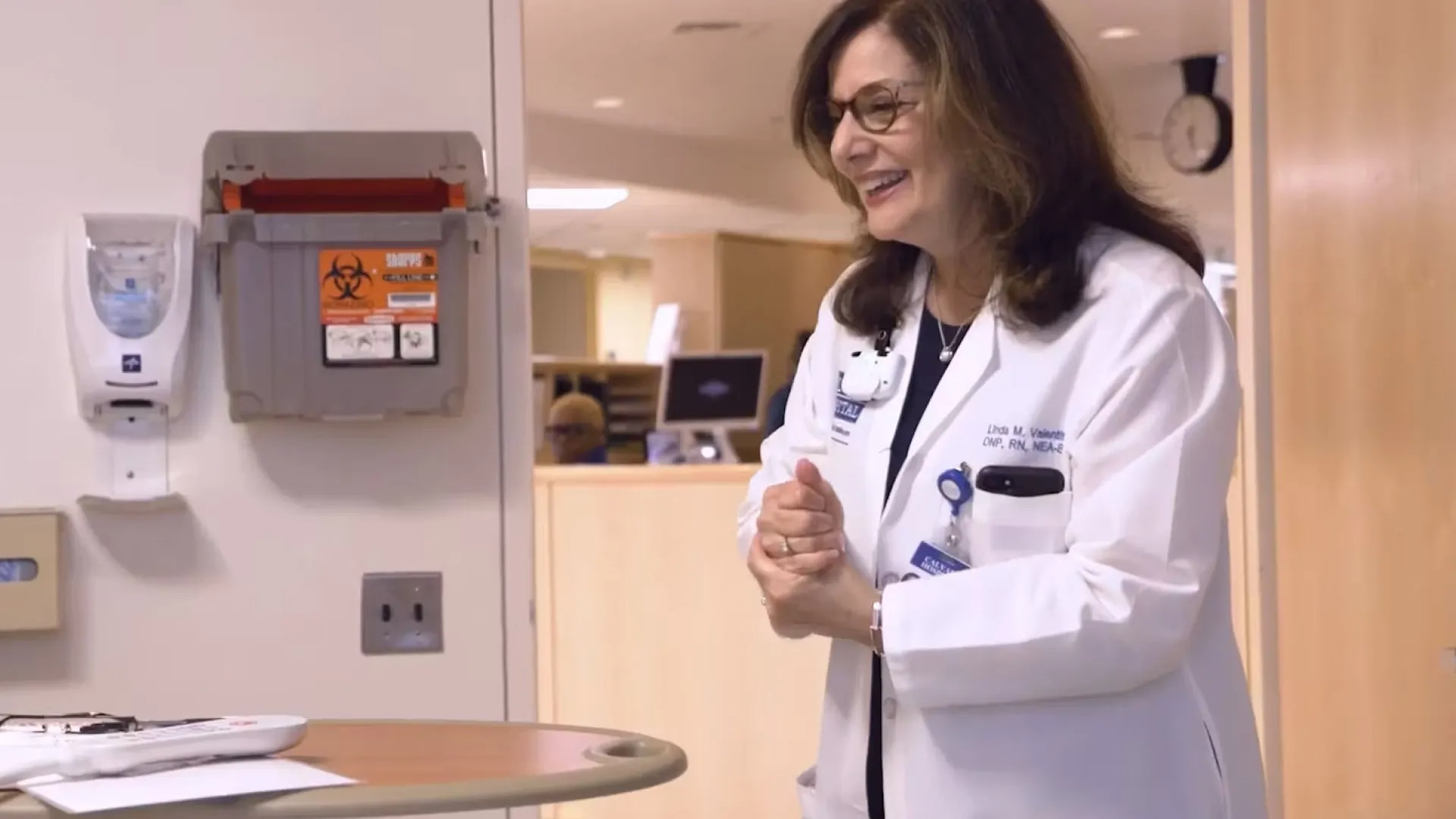 woman in a white lab coat enters a patient room in a hospital