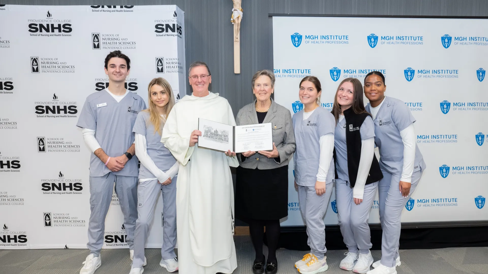 Seven people pose in front of two banners
