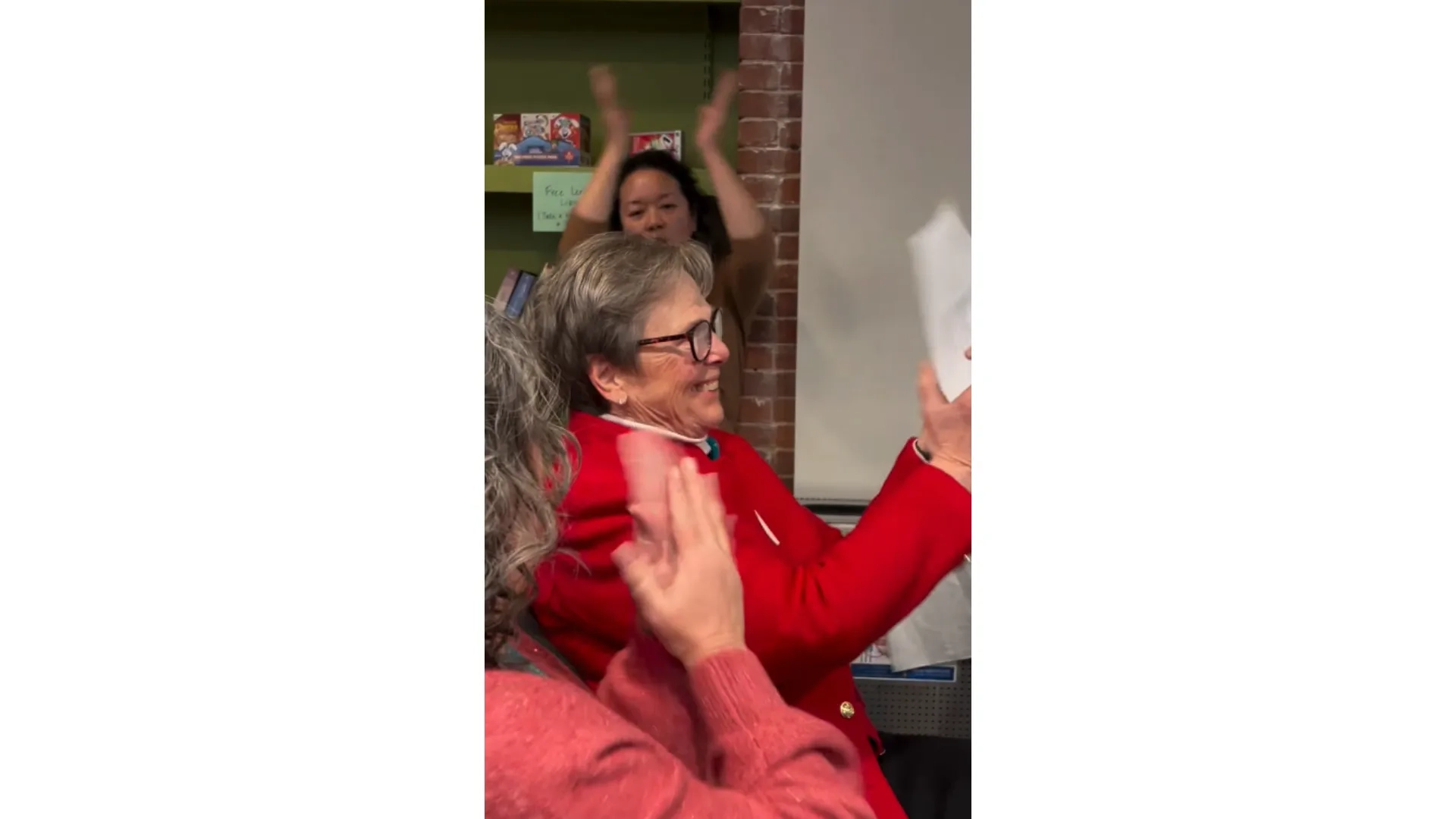 woman smiling and clapping with two women doing the same next to her