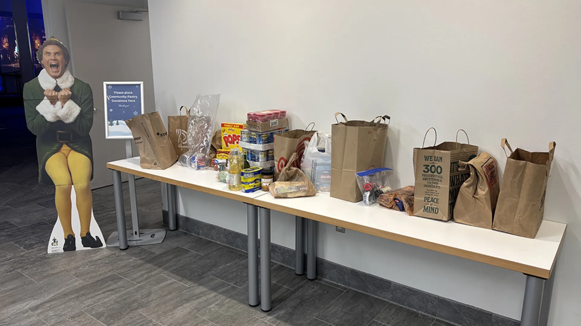 A long table with grocery bags, cans, and boxes of food