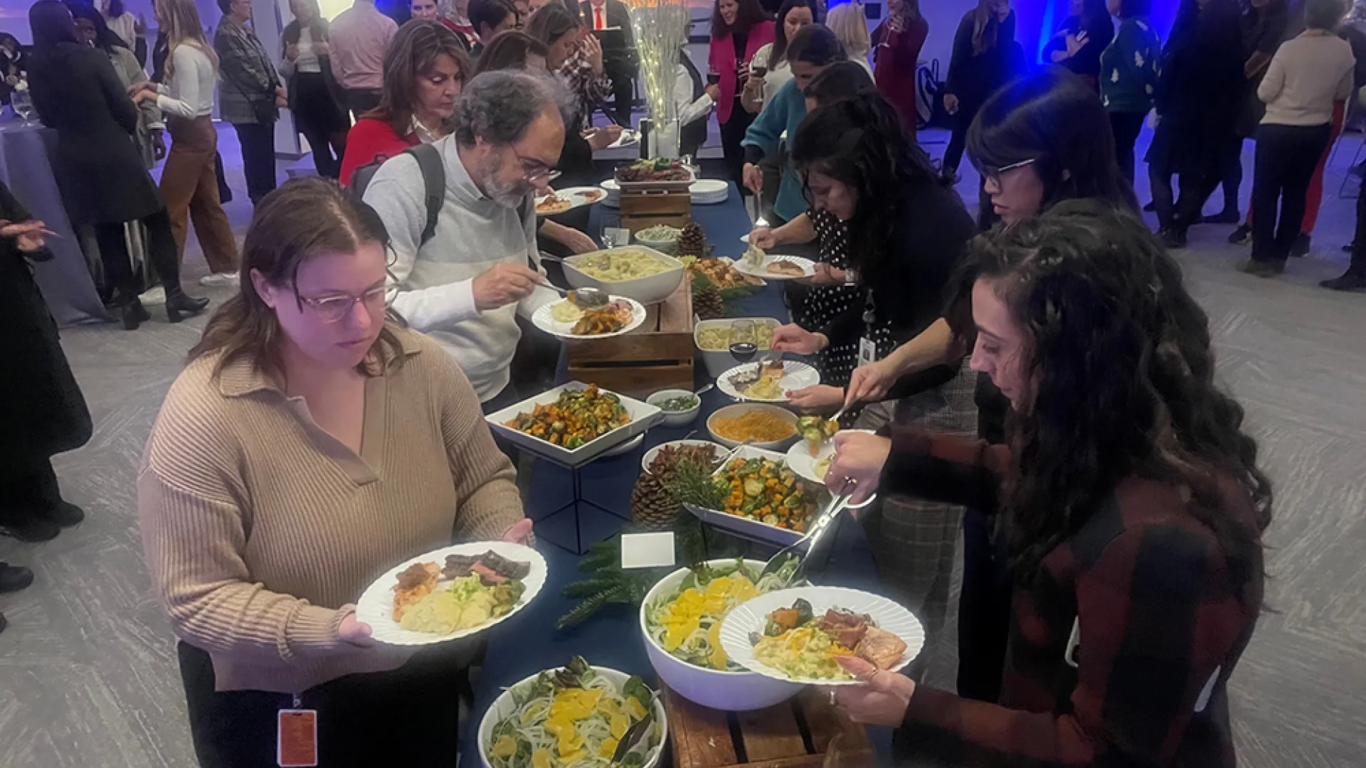 People at a party fill up food along a buffet line