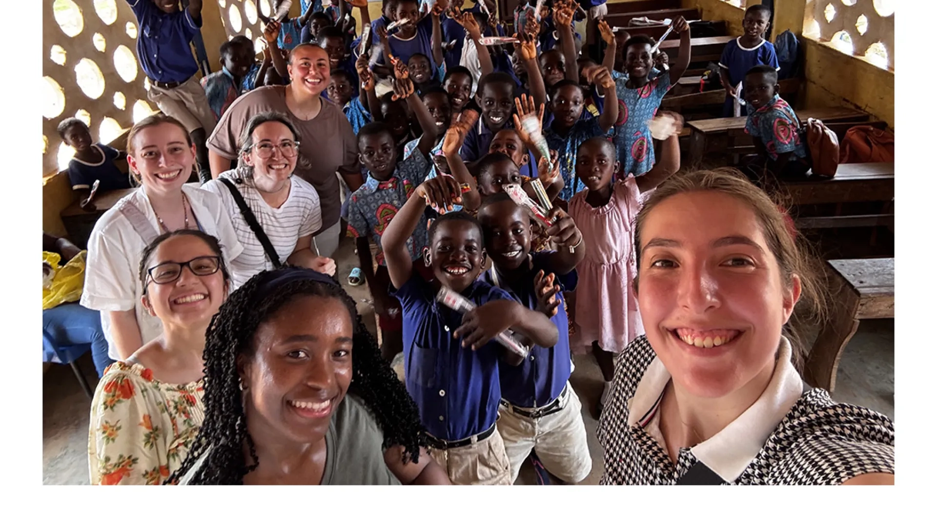 Adults pose for a photo while children in the background hold up their hands