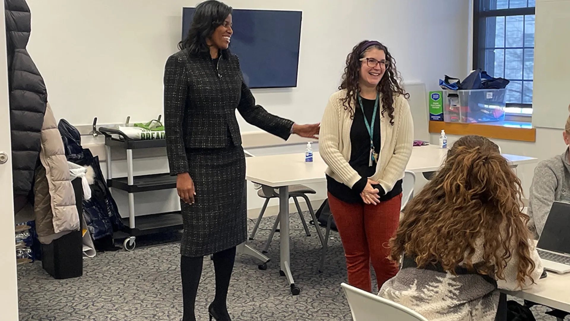 Two women stand facing a class with students at tables