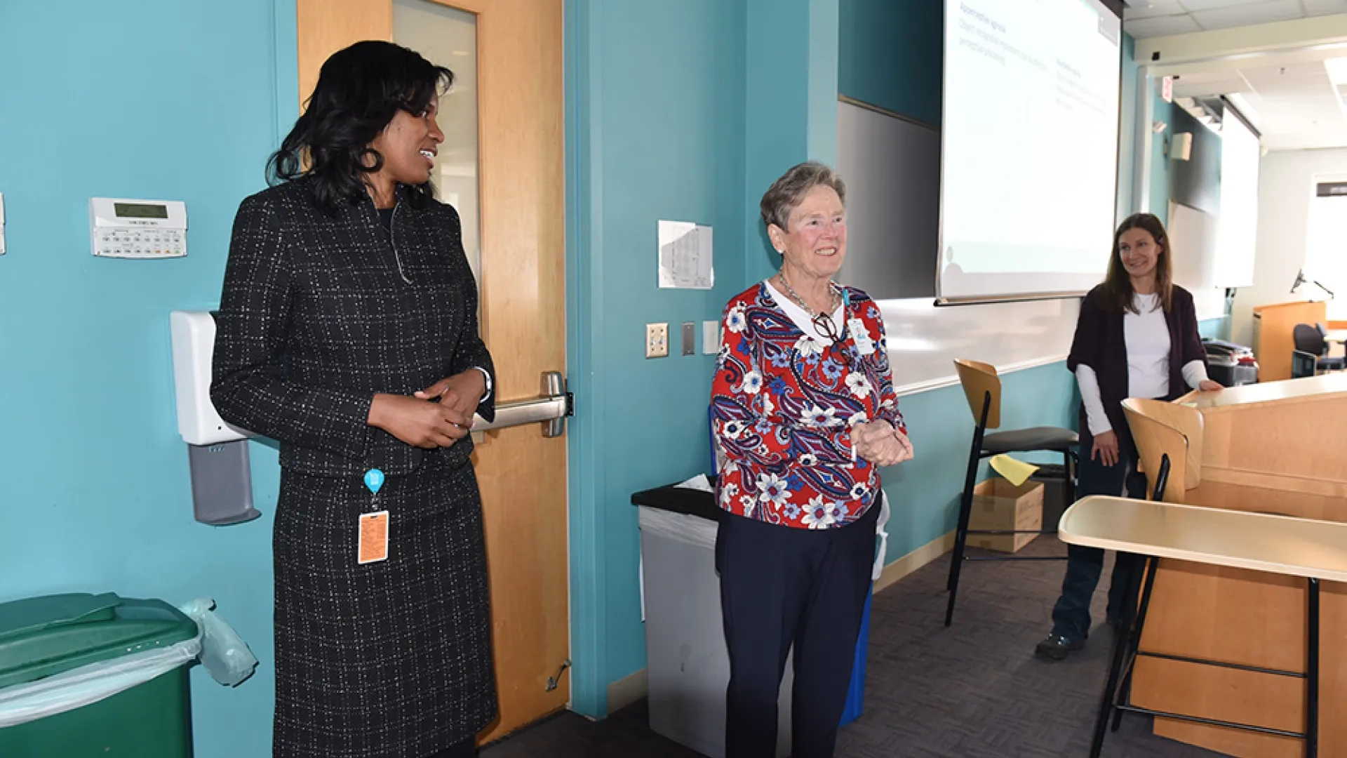 Two women stand inside a classroom door