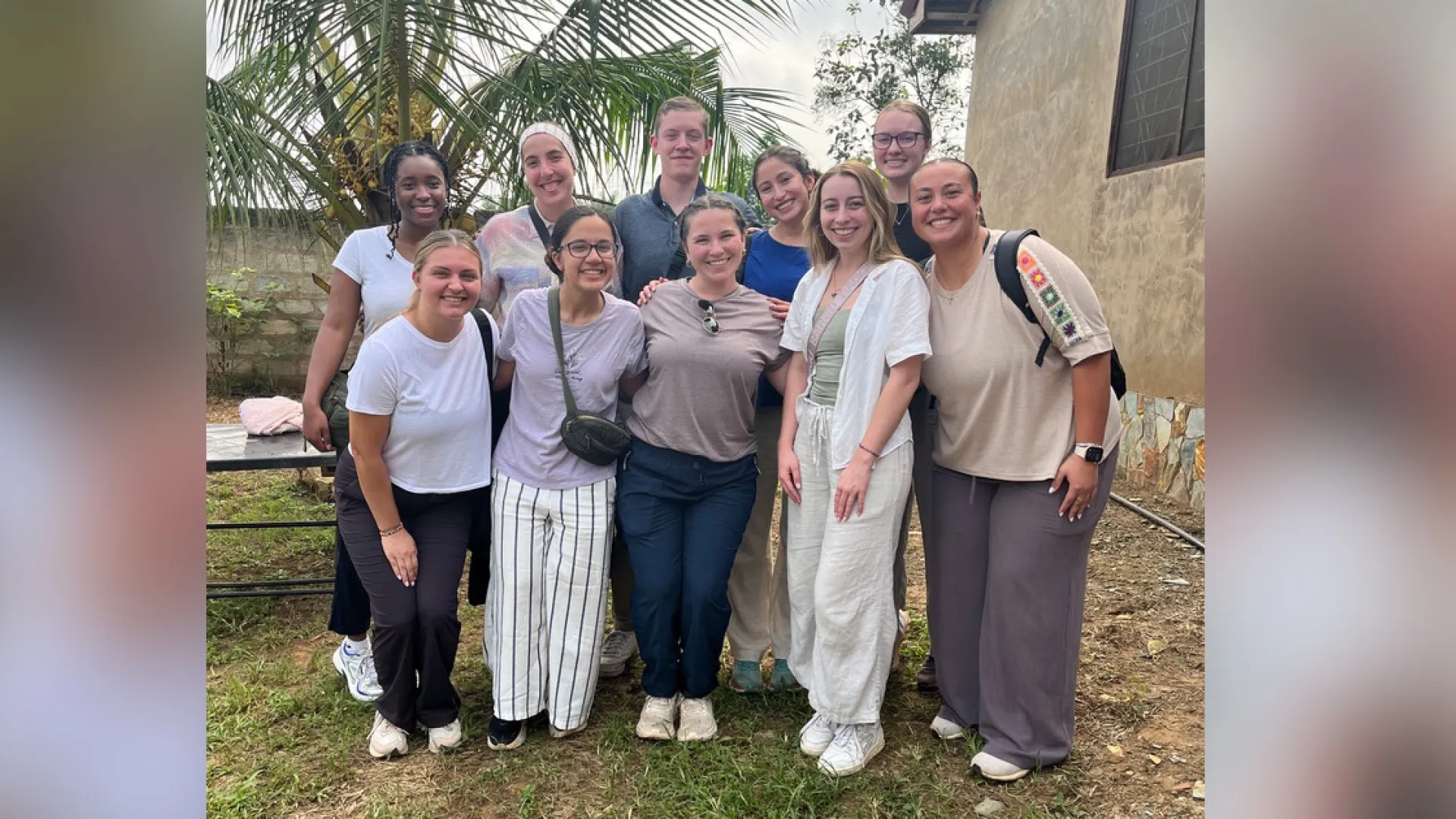 Ten people stand in two rows to pose for photo