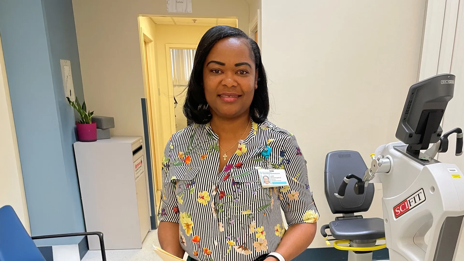 woman with manila folder standing in front of an exercise bike