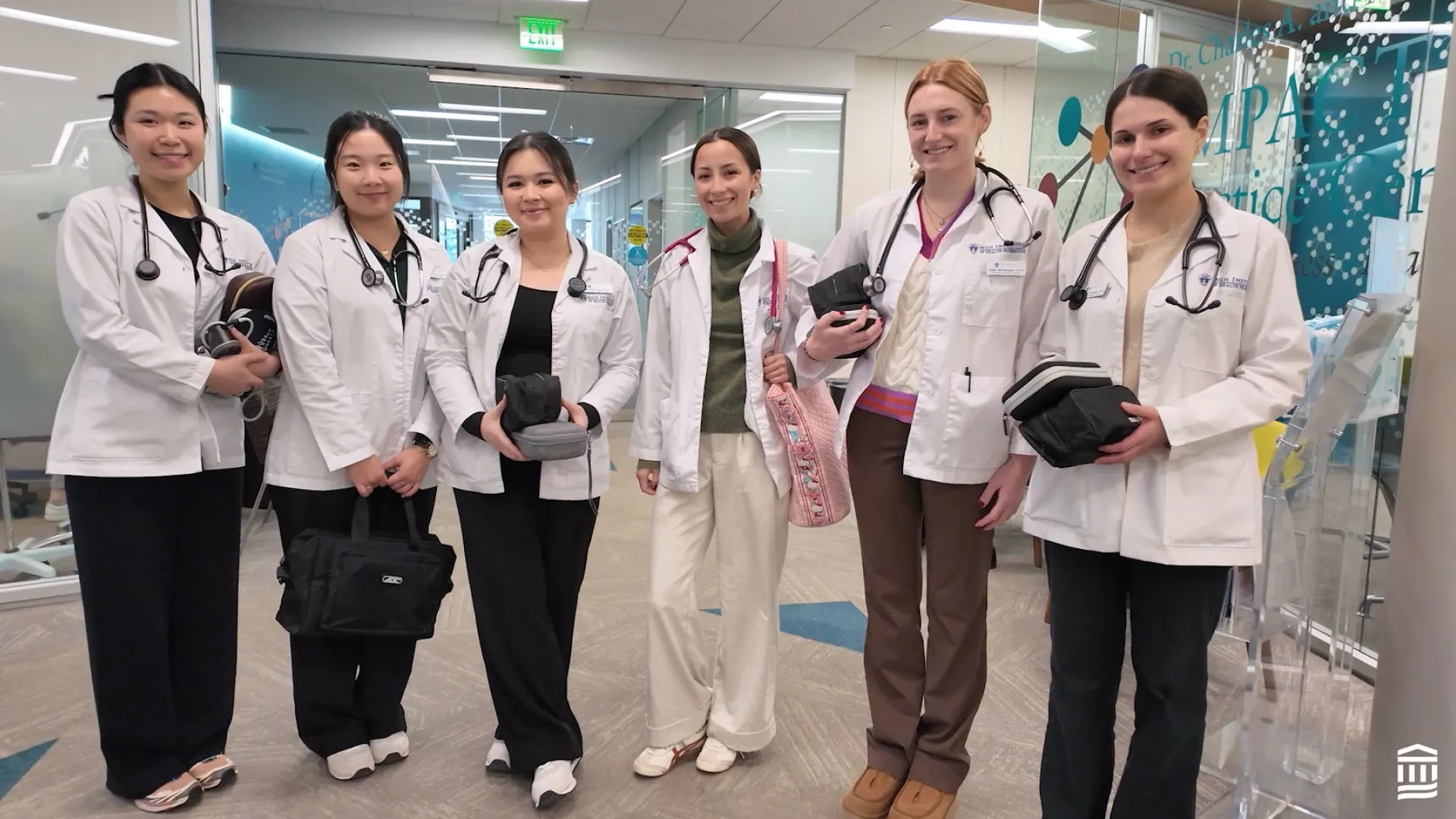 women with white medical coats on stand in a semi circle in the physician assistant program