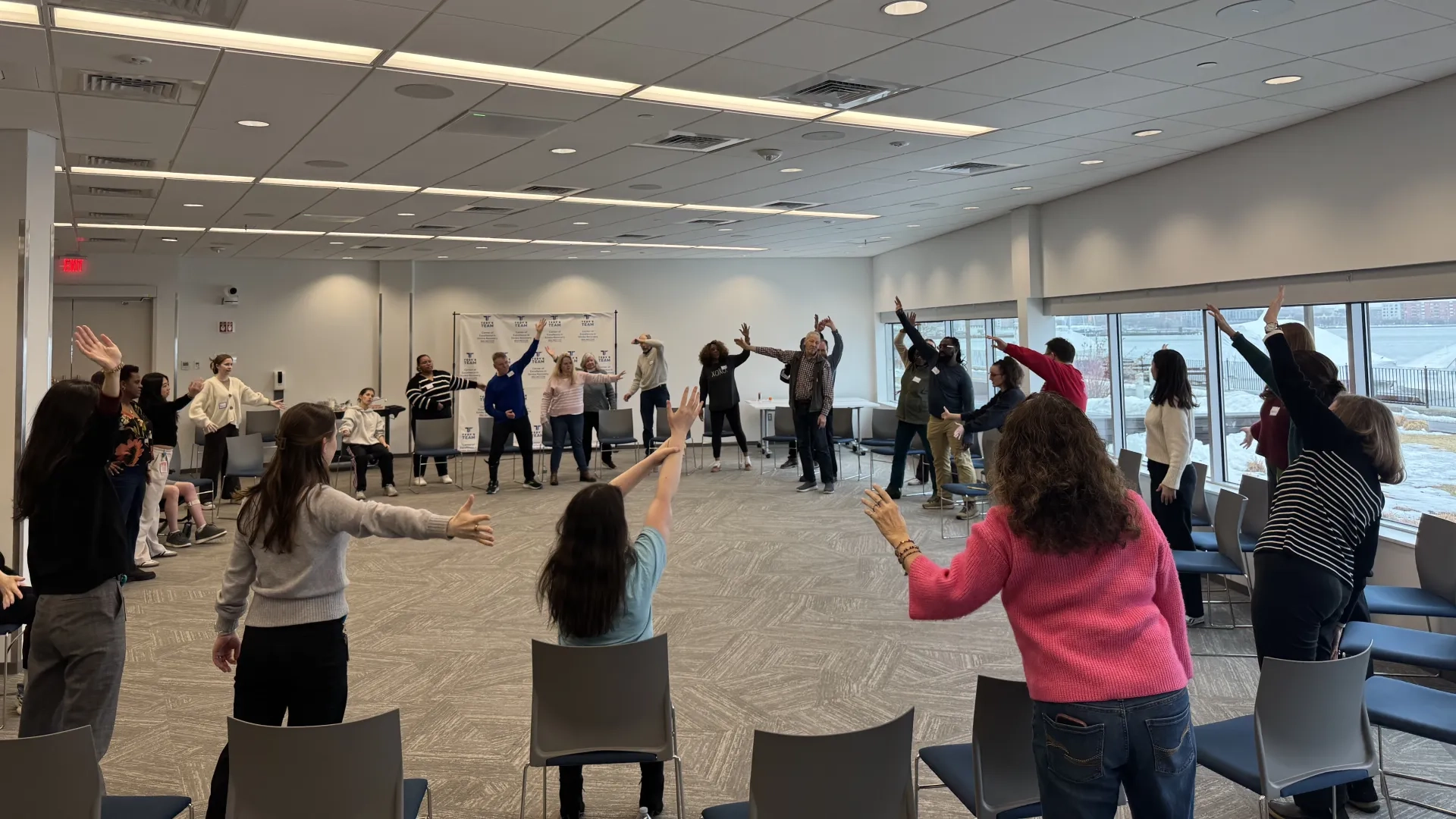 Group of people in a circle with their arms raised.