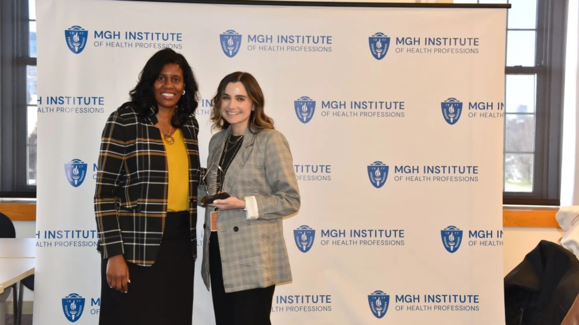 Two women posing in front of a backdrop
