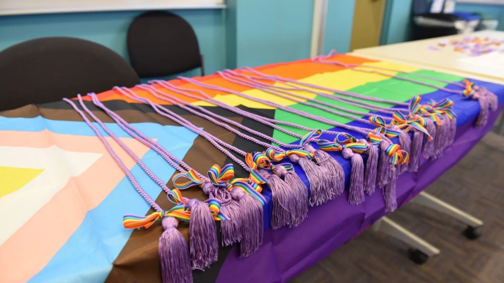 purple gradation cords laying on an LGBTQ+ flag on a table