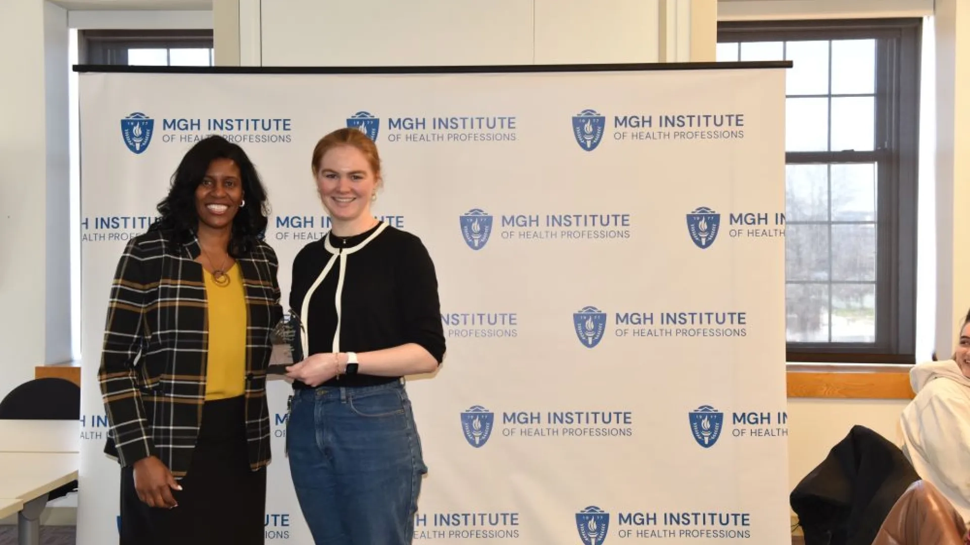 Two women standing in front of a backdrop 