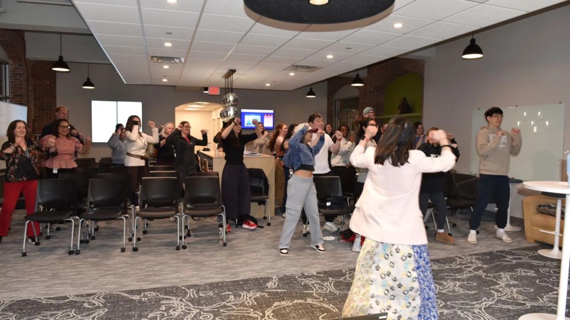 several people dancing and singing in a room 