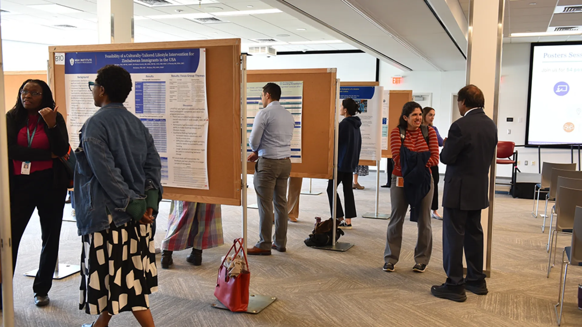 People stand at boards with scientific posters discussing their research with attendees