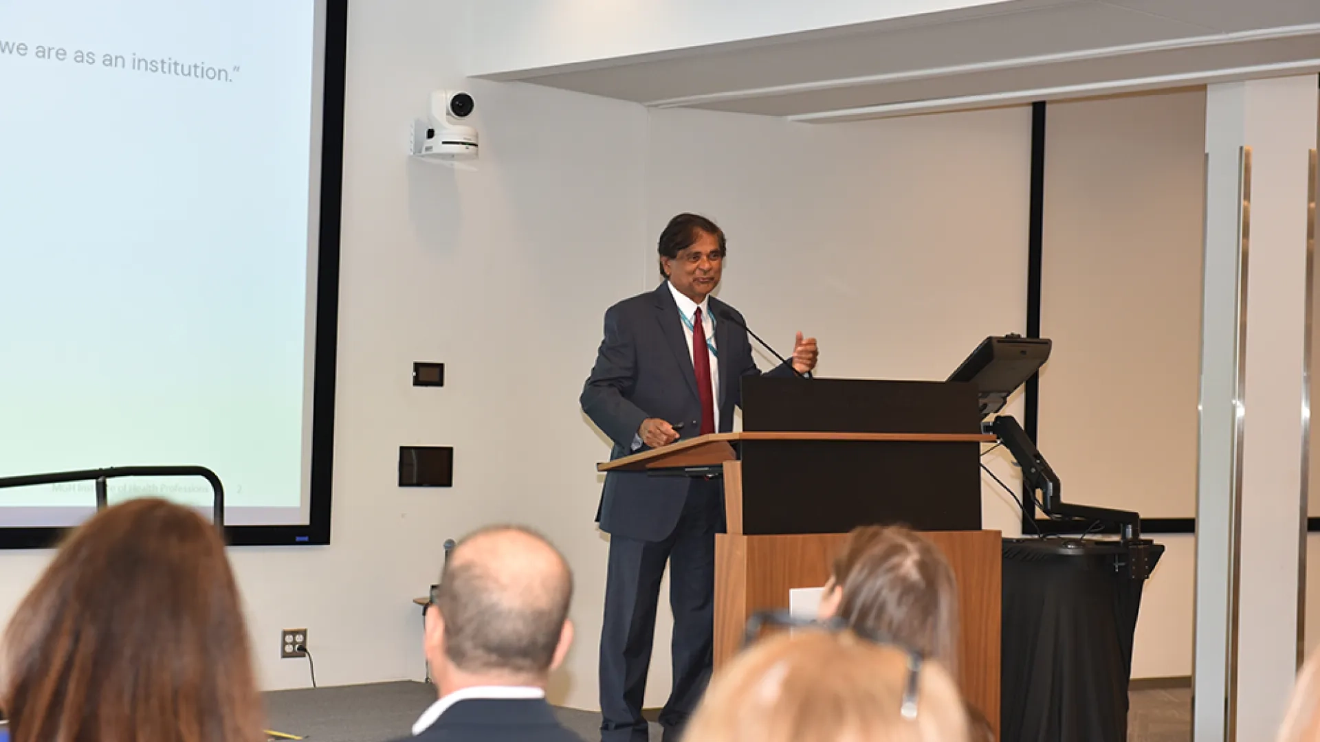 A man at a podium discusses research at the MGH Instittute