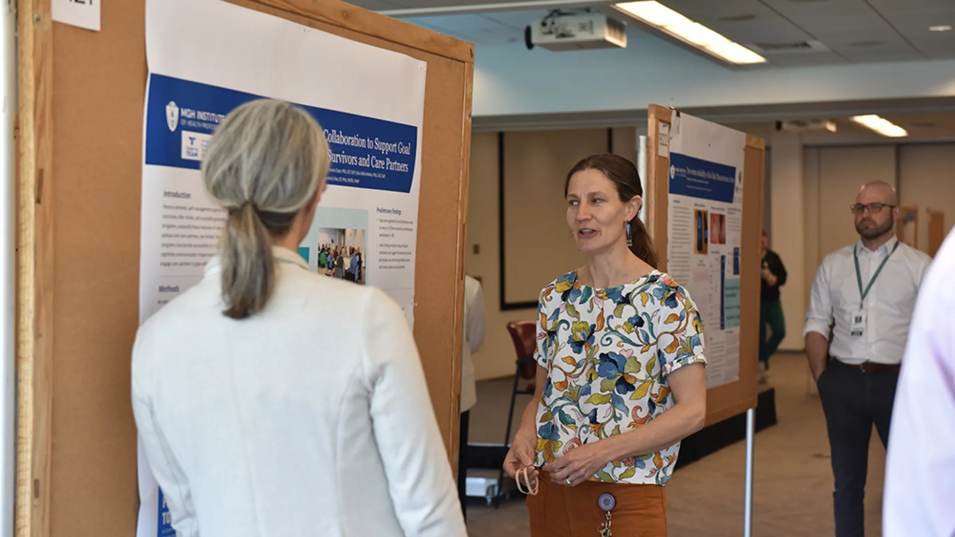 Two women discuss a poster on supporting stroke survivors and care partners