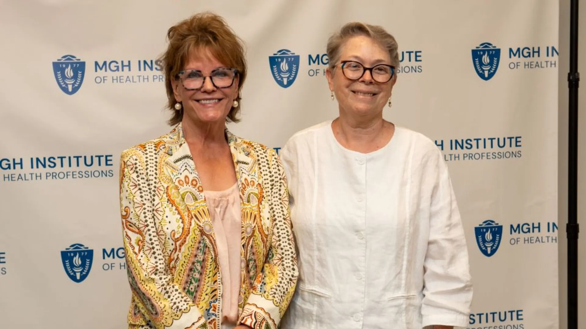 Two women standing in front of a backdrop