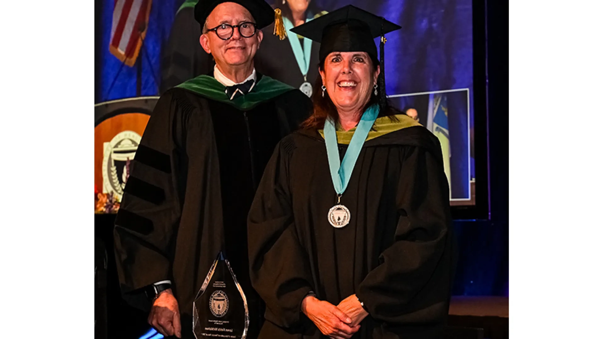 man and woman standing at a podium with a cap and gown 