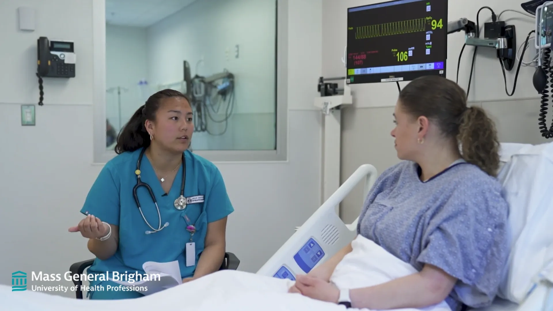 a nurse in scrubs sits next to a woman in a hospital bed