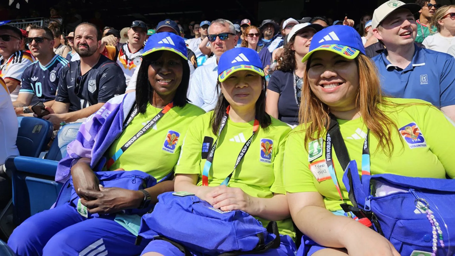 Three women sit in a stadium watching a World Cup game