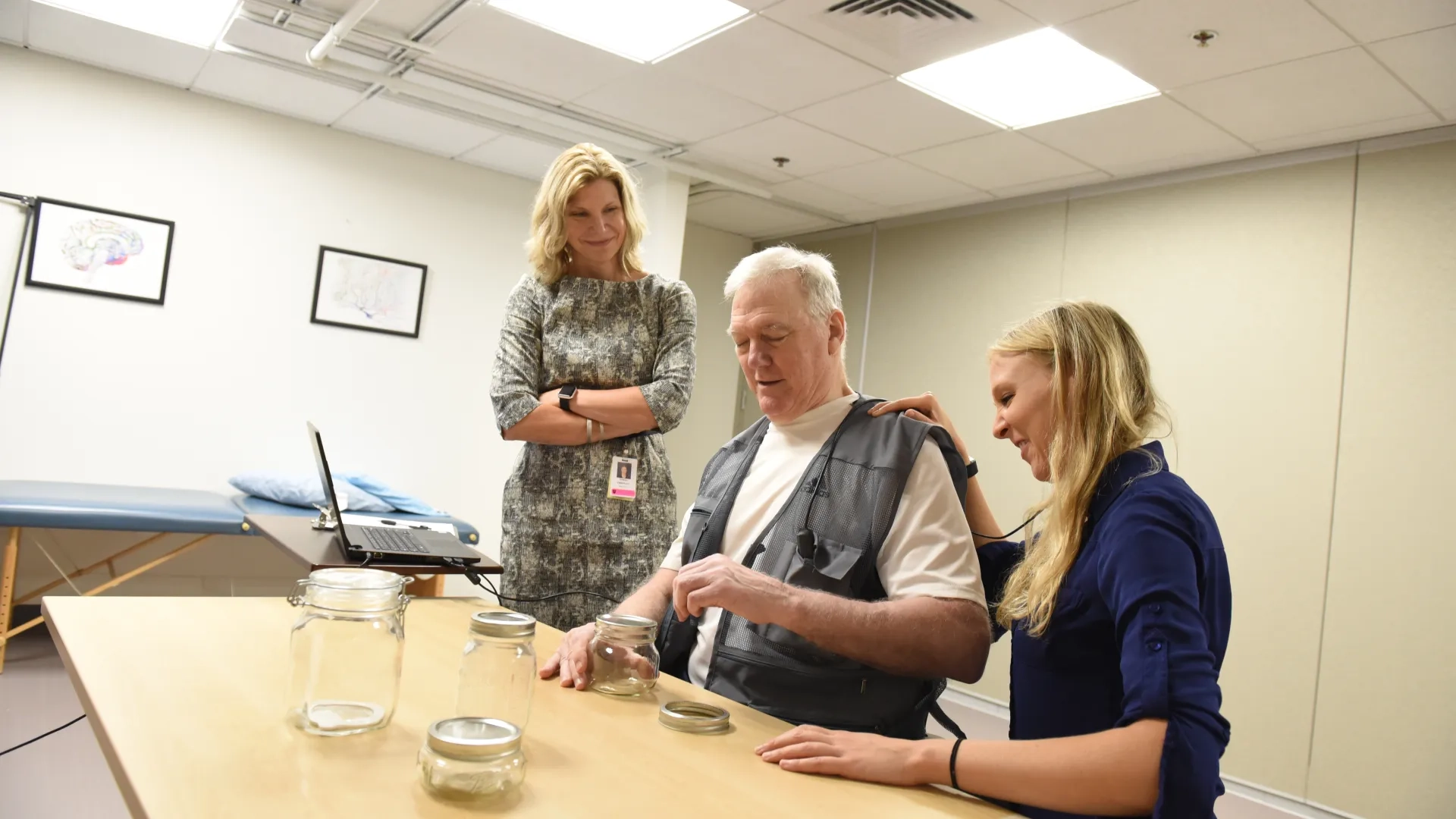 A stroke survivor is performing tasks while two physical therapists assist him