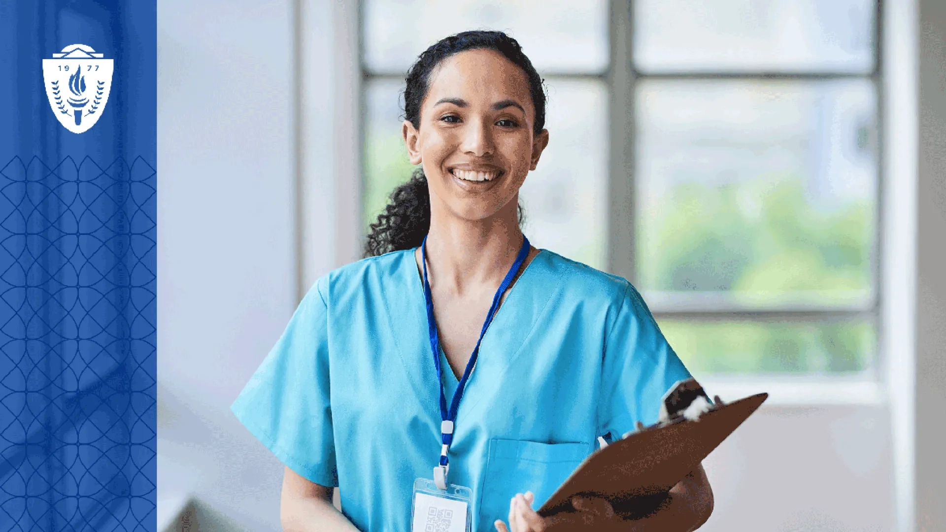Nurse holding a clipboard, wearing blue scrubs, and wearing a lanyard around her neck