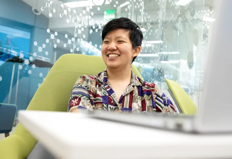 Person smiling in a chair with a laptop in front of them