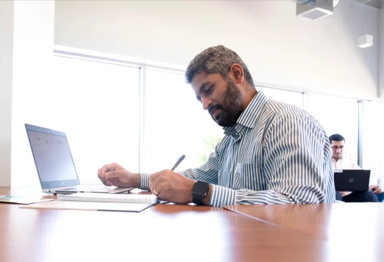 A man working at a desk with a notebook and laptop