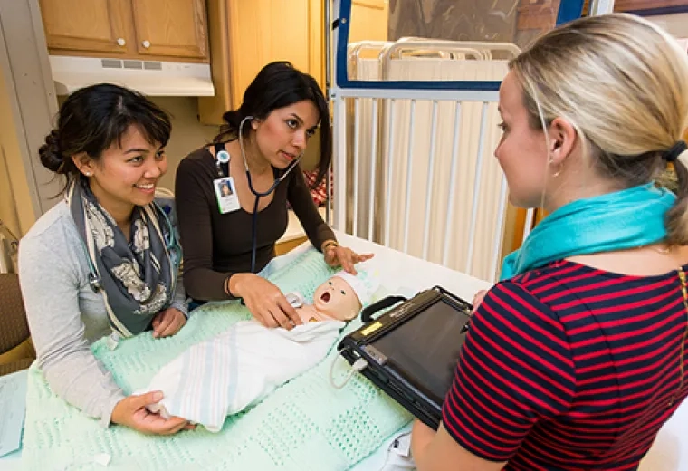 Three woman training on a mannequin doll