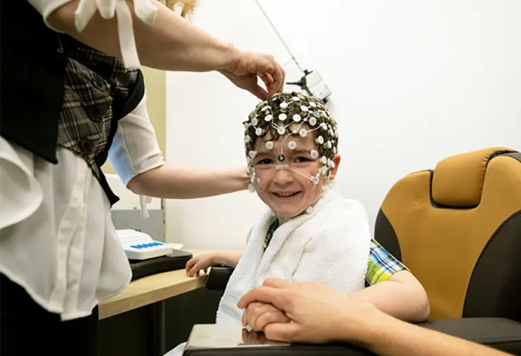 Researcher places round sensors on the head and face of a child