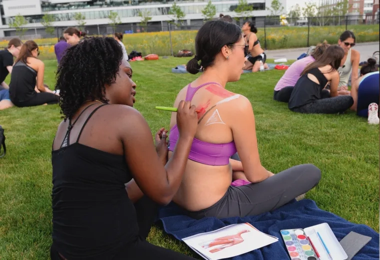 A field of people in small groups making body art on eachother
